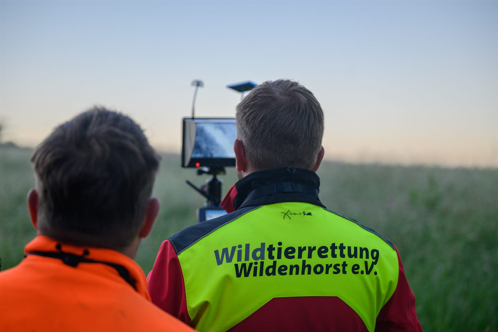 Zwei Teammitglieder von hinten, einer trägt eine Jacke mit der Aufschrift „Wildtierrettung Wildenhorst e.V.